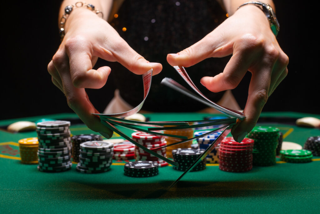 croupier shuffles poker cards in a casino on the background of a table, chips